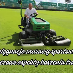 Mężczyzna na zielonej kosiarki jeździ po boisku sportowym.