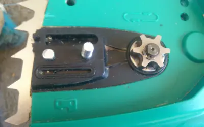 Widok z bliska na mechanizm piły elektrycznej, w tym zębatkę i elementy pompki oleju.